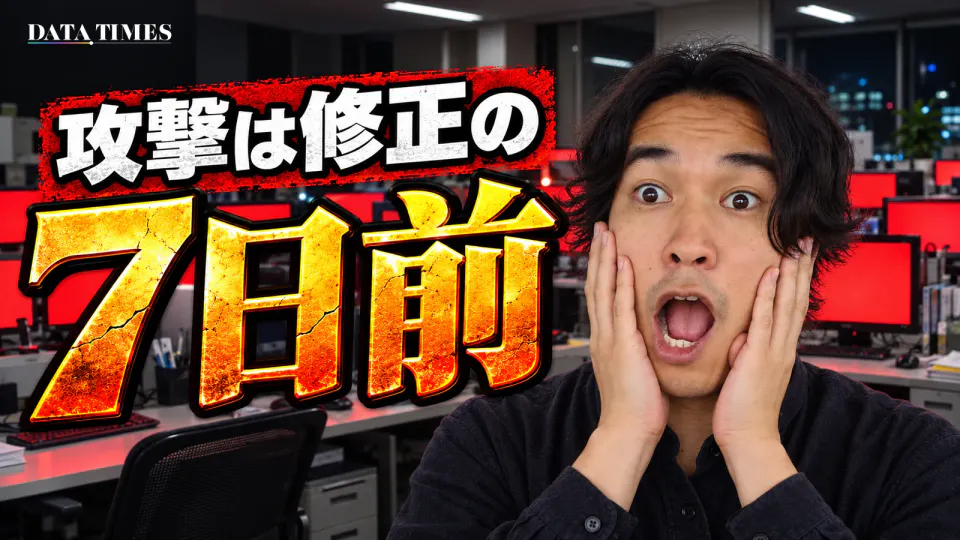 夜のオフィスで、並んだモニターがすべて真っ赤な警告画面になっている。左に白い文字で「攻撃は修正の」、その下に金色のひび割れた大きな文字で「7日前」。右でDATA TIMES編集長の小笠原海人が両手をほおに当て、目と口を大きく開けて驚いている