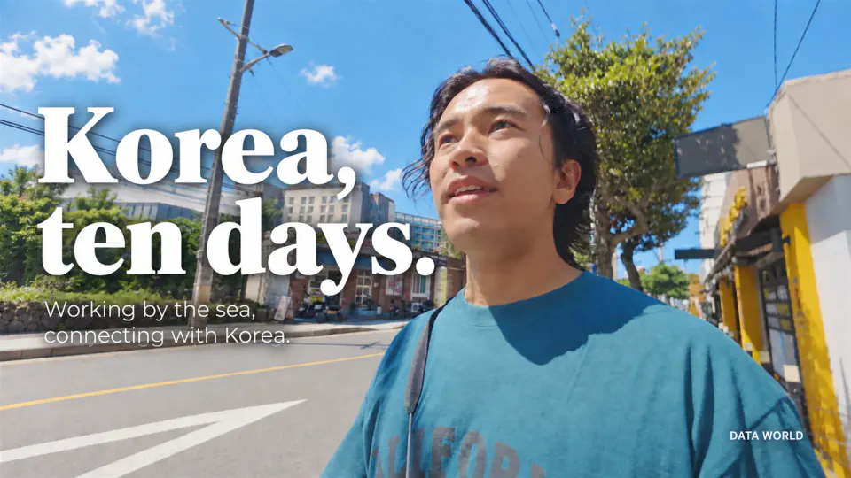 DATA TIMES editor-in-chief Kaito Ogasawara looking up at the sky on a street in Jeju. Text: Korea, ten days. Working by the sea, connecting with Korea