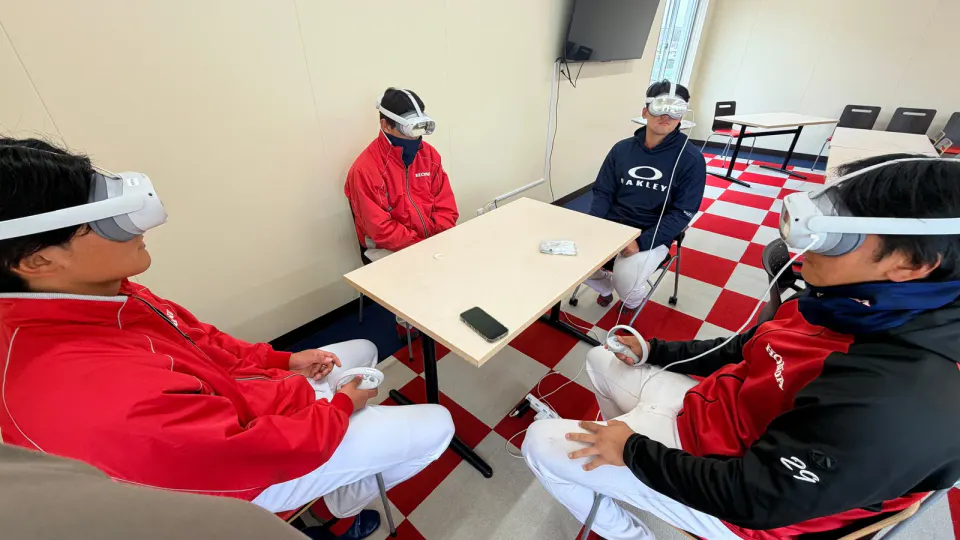 Honda baseball players sit in a meeting room wearing white VR headsets while their brain fatigue is measured